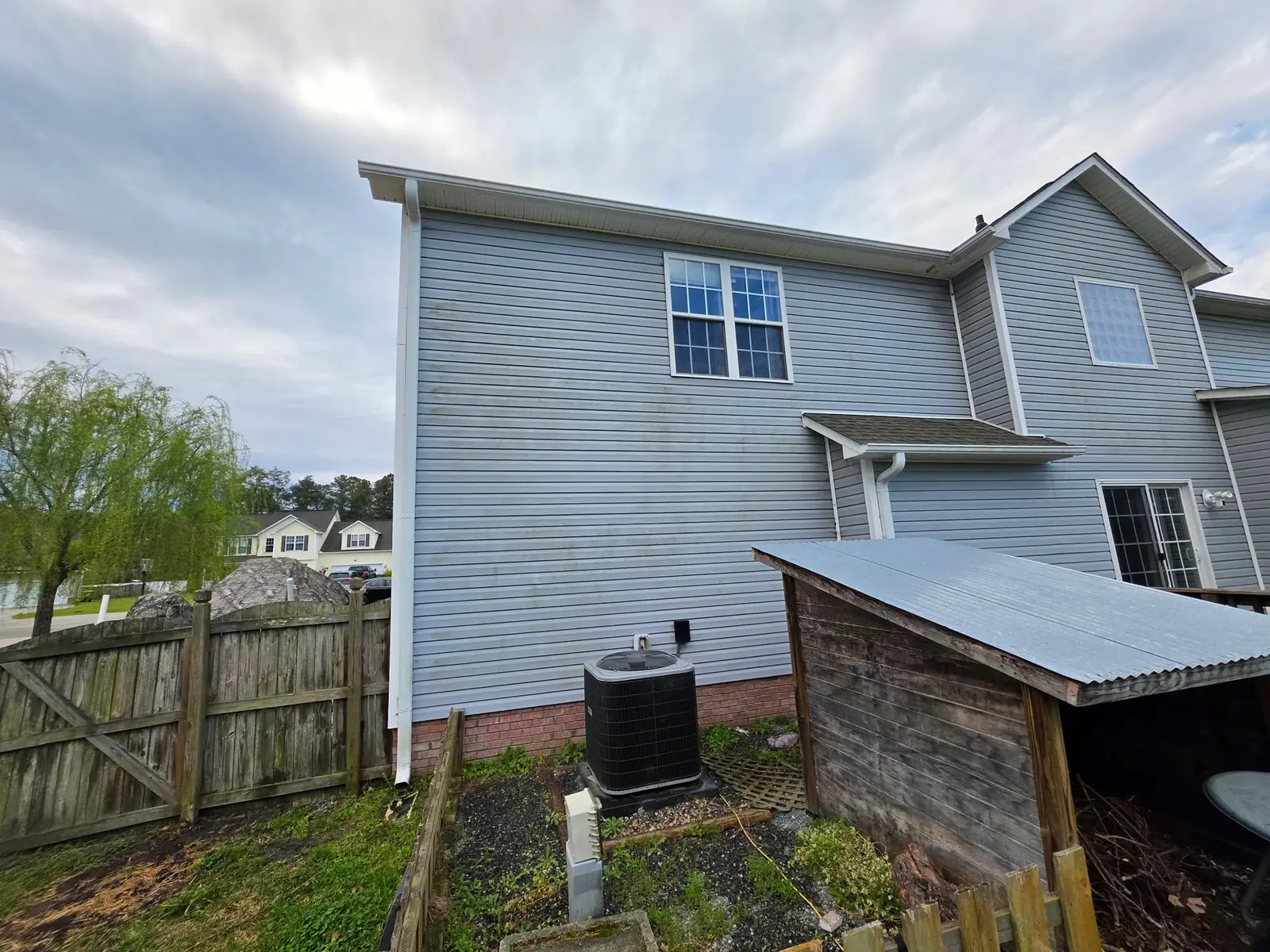 Before: two-story house siding with algae and weathering buildup
