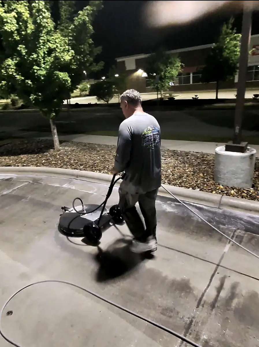 Fresh Start Surface Solutions running a rotary surface cleaner on a restaurant drive-through lane at night in Jacksonville, NC
