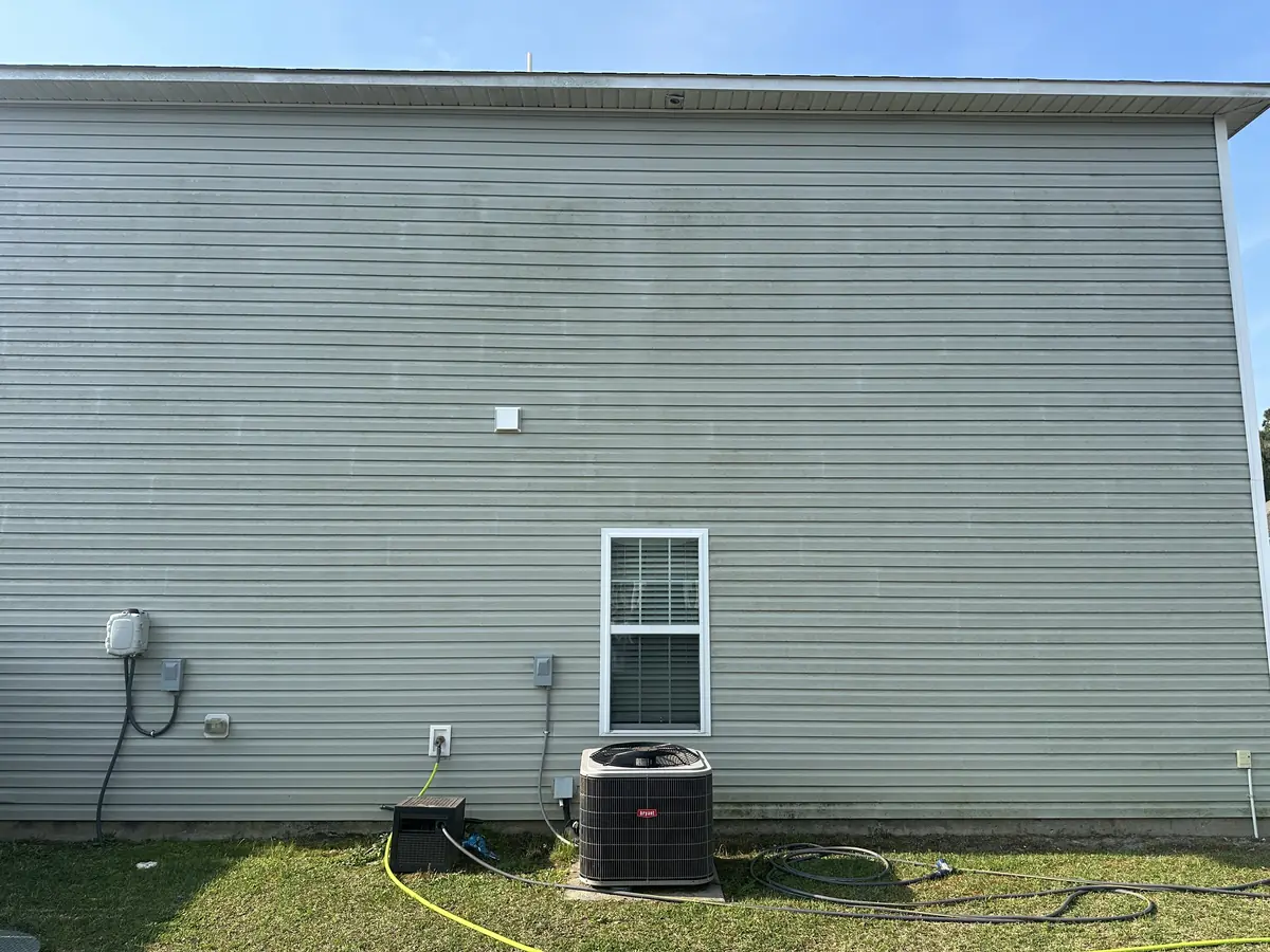 Before: gray vinyl home with algae and biological staining on siding before soft wash treatment