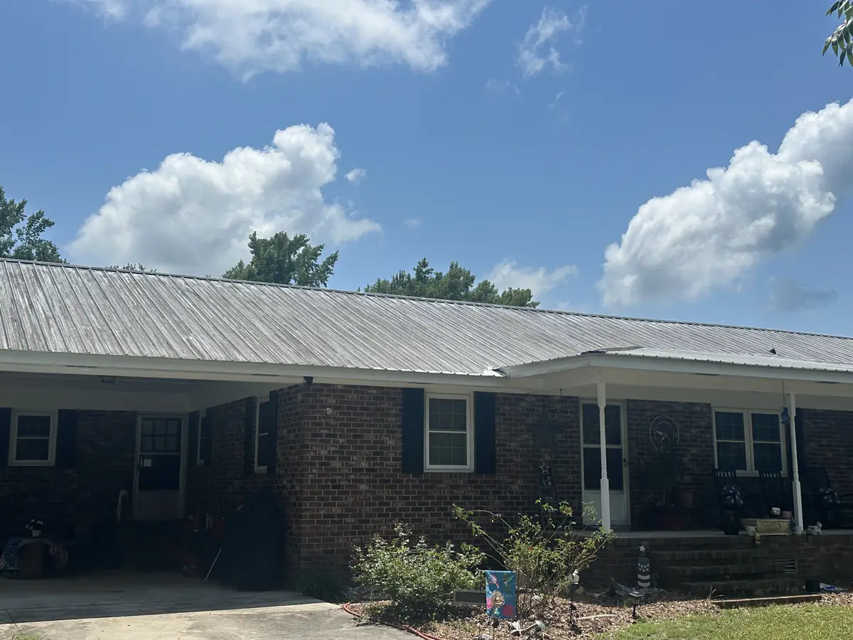 Before: white metal roof on a Jacksonville, NC home covered in heavy oxidation, algae streaking, and dark staining