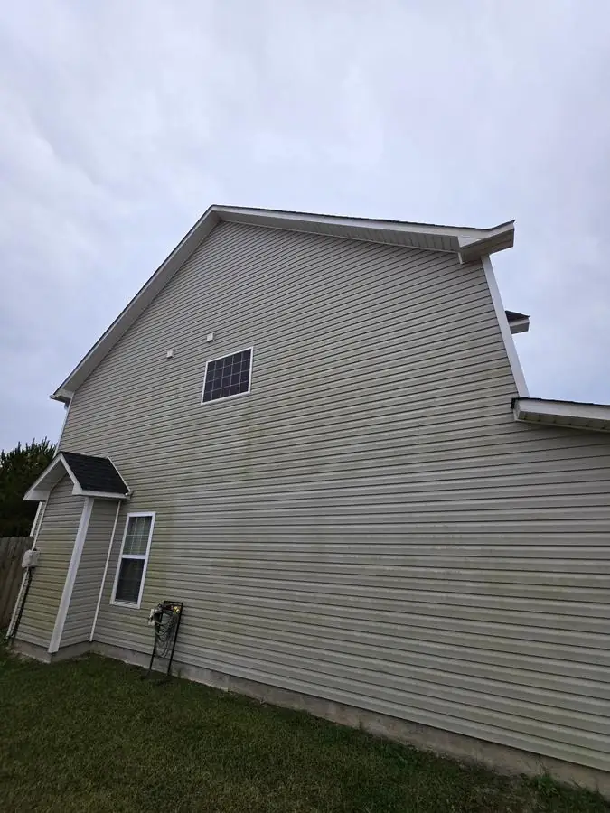 Before: house corner and gutters with dark algae streaks and staining