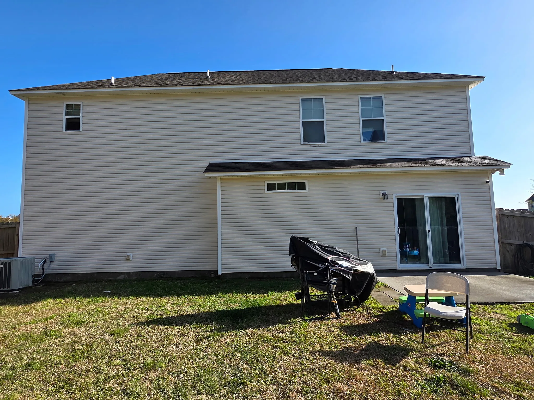 After: two-story home rear fully cleaned, siding and patio restored
