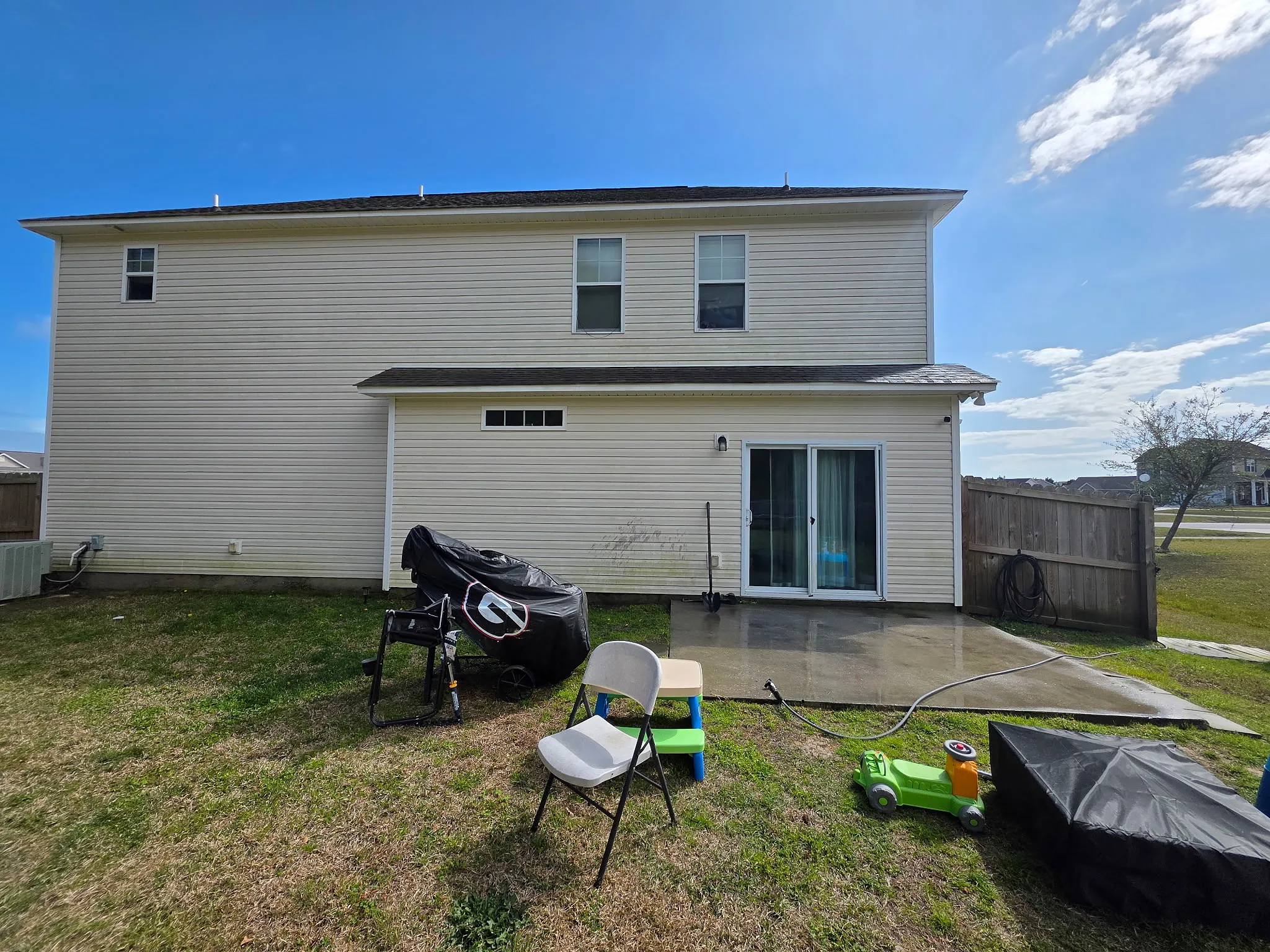 Before: two-story home rear exterior and patio being cleaned