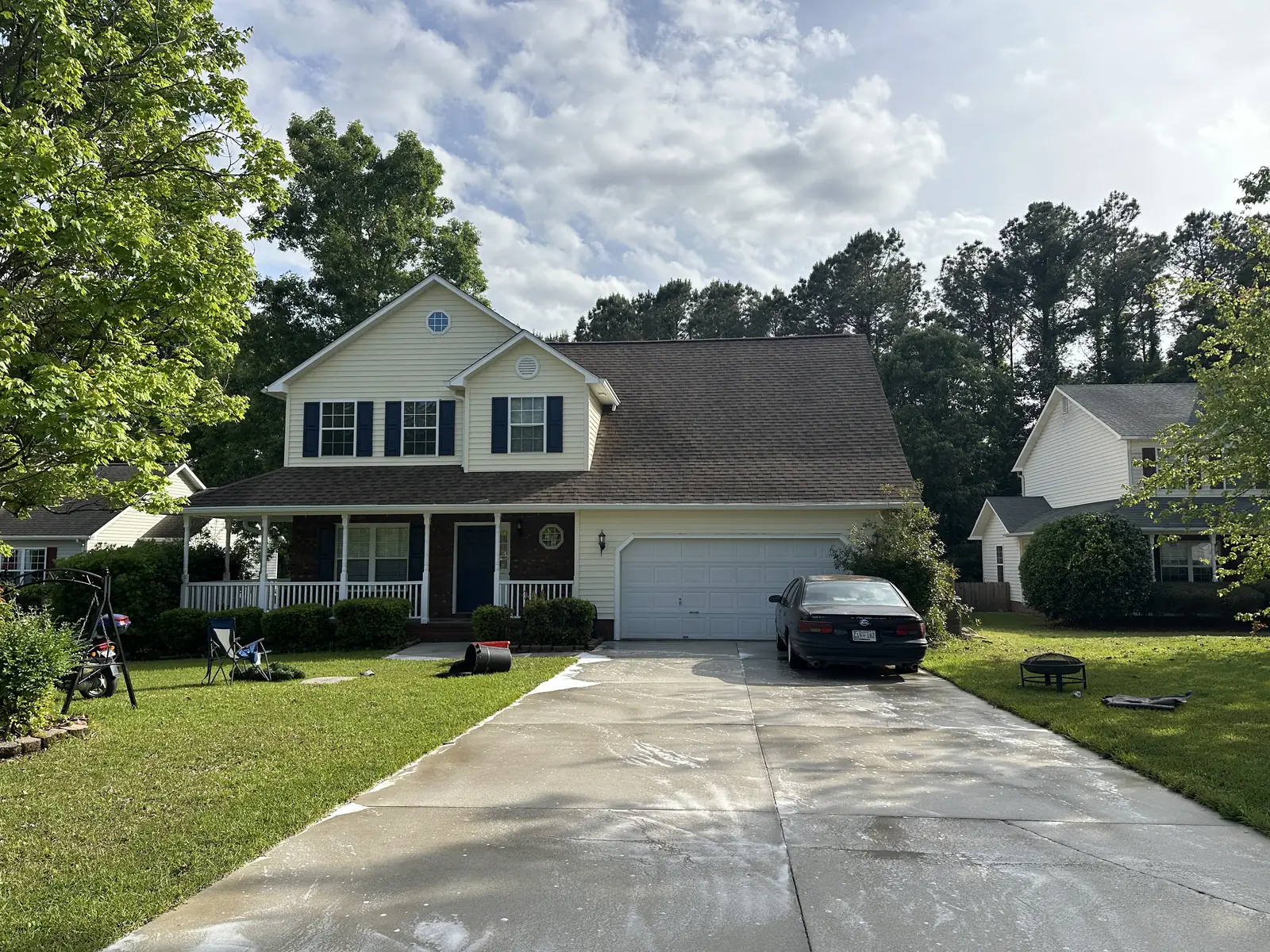 After: two-story yellow house and concrete driveway fully cleaned and restored