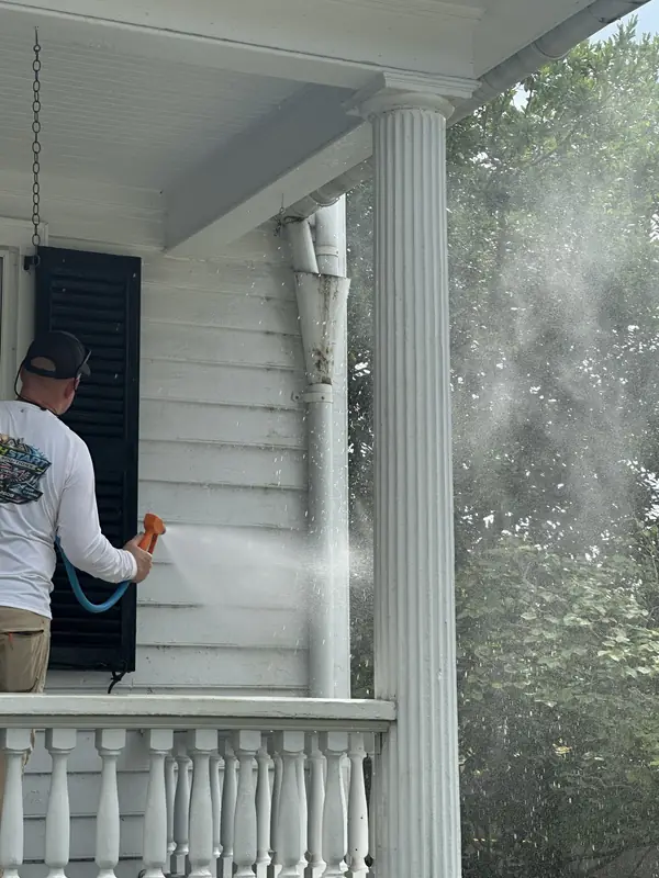Fresh Start technician soft washing the painted wood siding of a historic New Bern home with a low-pressure nozzle