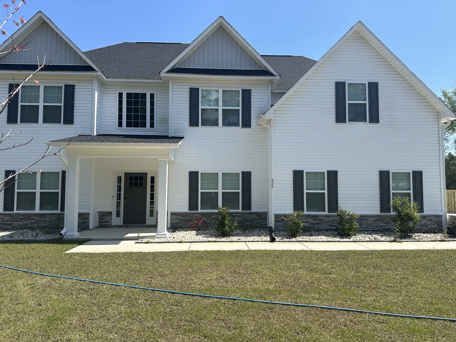 Before: white colonial house with algae and mildew staining on siding — Jacksonville, NC